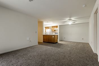 A room with a carpeted floor and a wooden cabinet in the corner at Pheasant Run Apartments, Lafayette